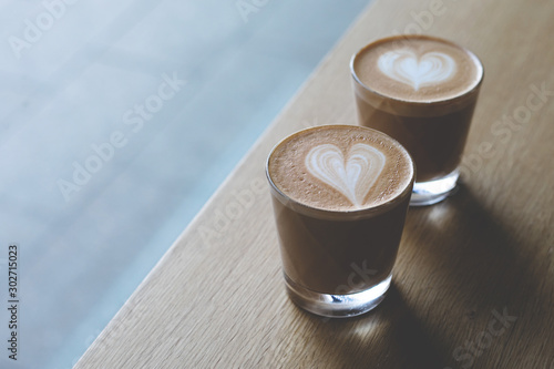 Two glasse cups of capuccino on the wooden table. photo