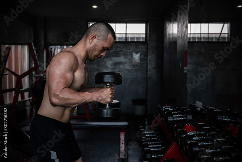 Portrait of asian man big muscle at the gym,Thailand people,Workout for good healthy,Body weight training,Fitness at the gym concept,Prank to abdominal muscles,Lift up dumpbell