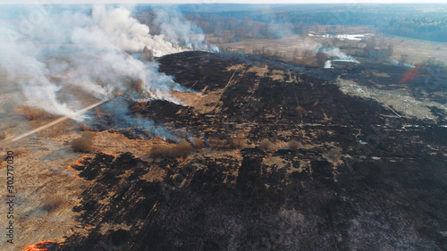 Forest and field fire. Dry grass burns, natural disaster. Aerial view. A large burned field, burning occurs on the banks of a small river.