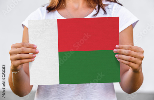 woman holds flag of Madagascar on paper sheet