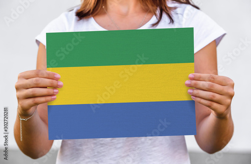 woman holds flag of Gabon on paper sheet