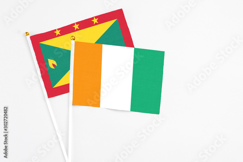 Cote D'Ivoire and Grenada stick flags on white background. High quality fabric, miniature national flag. Peaceful global concept.White floor for copy space.