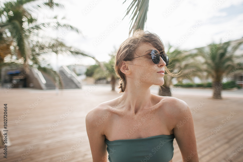 young sporty woman relaxing near palm tree