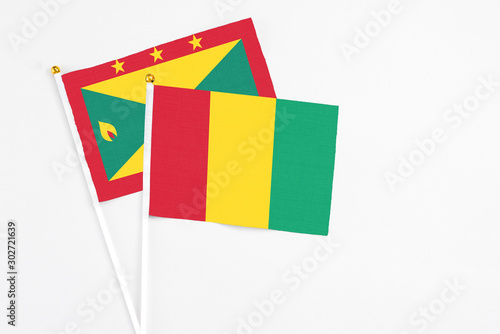 Guinea and Grenada stick flags on white background. High quality fabric, miniature national flag. Peaceful global concept.White floor for copy space.