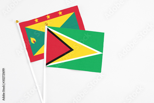 Guyana and Grenada stick flags on white background. High quality fabric, miniature national flag. Peaceful global concept.White floor for copy space.