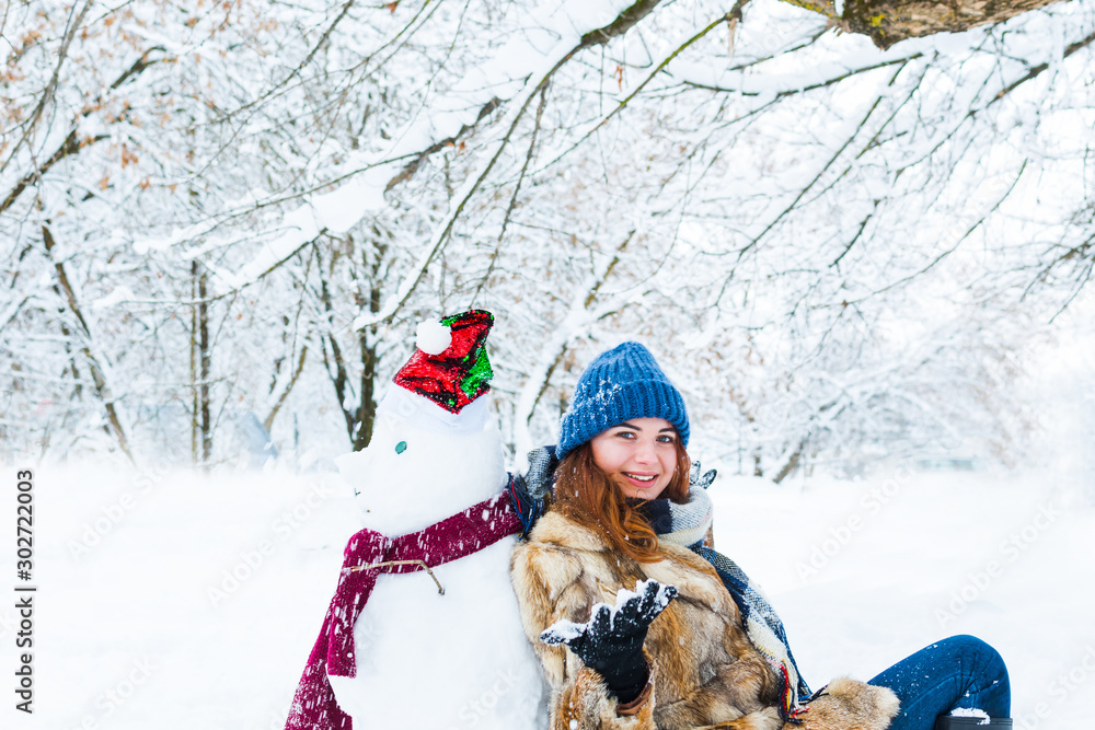 young beautiful woman playing with snowman young beautiful woman playing with snowman