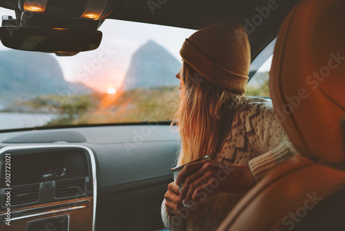 Woman on road trip traveling by rental car relaxing with coffee cup adventure lifestyle vacations vibes outdoor sunset Norway mountains view in window photo