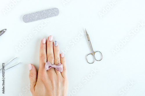 Female hand with pink nails and a bow as decoration concept of hands care at home or in salon © Leart