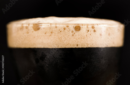 Wallpaper Mural Glass of dark beer isolated on black background. Foam close up.