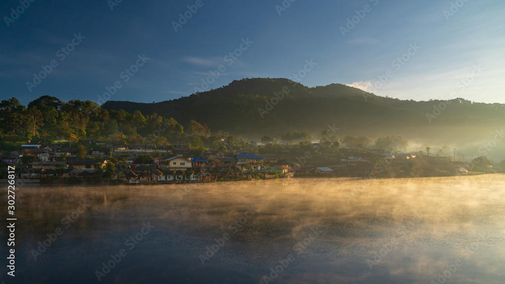 Morning view of Ban Rak Thai Village,Chinese Yunnan village on lakeside with green hill,sunlight,fog and clear sky background, Ban Rak Thai,Mae Hong Son, northern of Thailand.