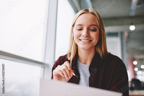 Fotografie Positive blonde woman fill in information in questionnaire making application fo