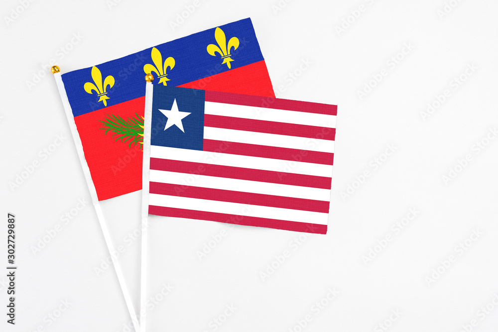 Liberia and Guadeloupe stick flags on white background. High quality fabric, miniature national flag. Peaceful global concept.White floor for copy space. Liberia and Guadeloupe stick flags on white background. High quality fabric, miniature national flag. Peaceful global concept.White floor for copy space.