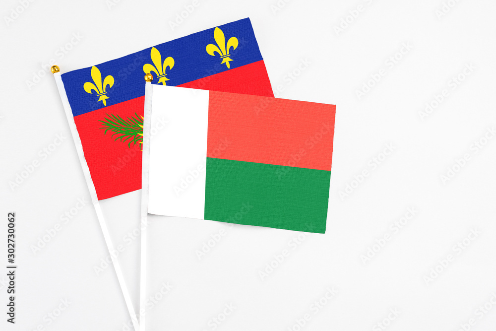 Madagascar and Guadeloupe stick flags on white background. High quality fabric, miniature national flag. Peaceful global concept.White floor for copy space. Madagascar and Guadeloupe stick flags on white background. High quality fabric, miniature national flag. Peaceful global concept.White floor for copy space.