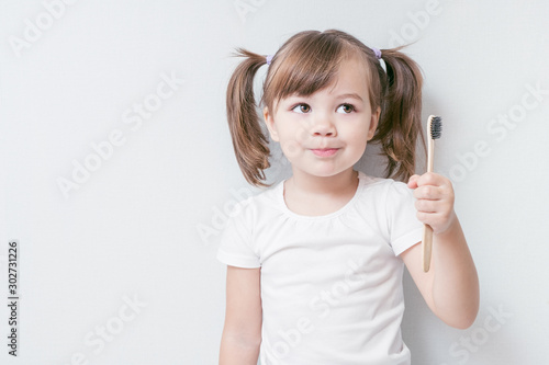 child girl brushes her teeth with a bamboo toothbrush. concept: environmental care, zero waste, ecology