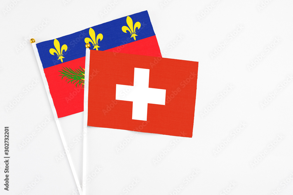 Switzerland and Guadeloupe stick flags on white background. High quality fabric, miniature national flag. Peaceful global concept.White floor for copy space.