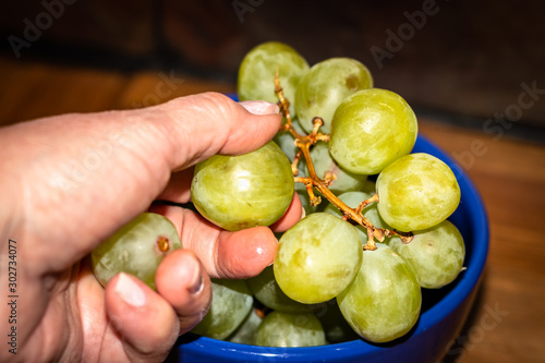 Green grapes in a blue bowl held by a hand