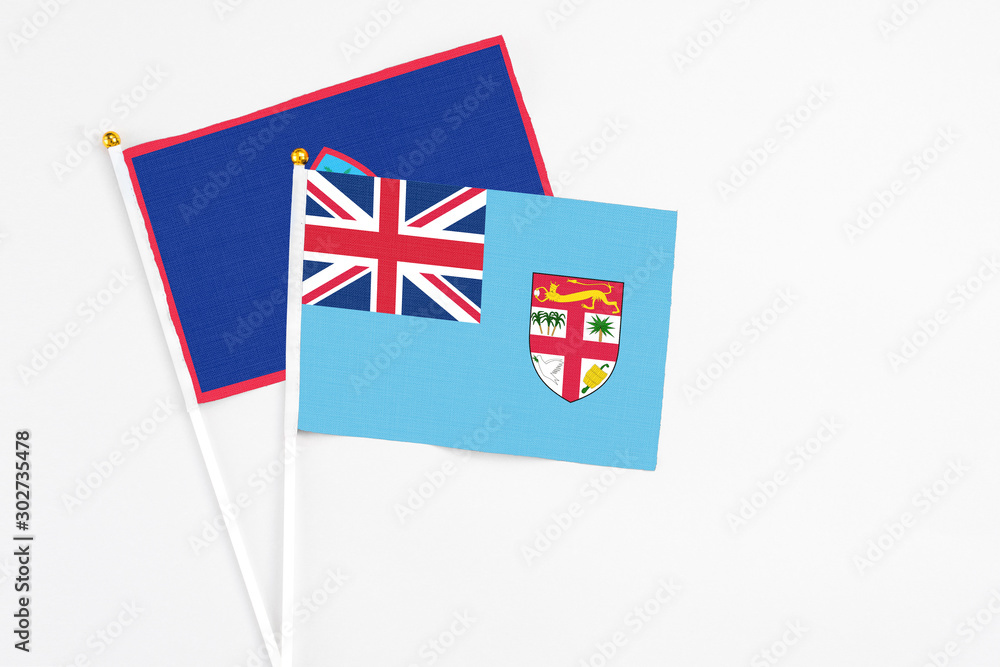 Fototapeta premium Fiji and Guam stick flags on white background. High quality fabric, miniature national flag. Peaceful global concept.White floor for copy space.