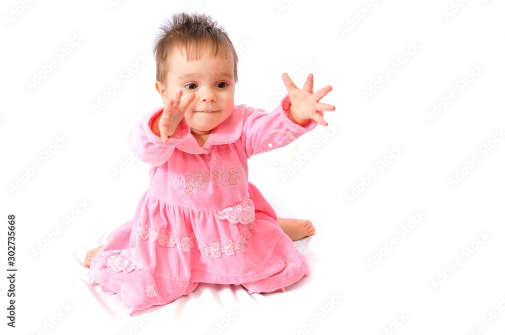 Funny surprised little girl in pink dress plays with soap bubbles on white isolated background. Happy childhood Funny surprised little girl in pink dress plays with soap bubbles on white isolated background. Happy childhood