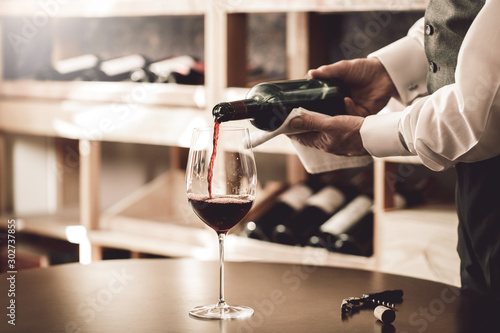 Sommelier Concept. Senior man standing pouring wine into glass elegant close-up photo