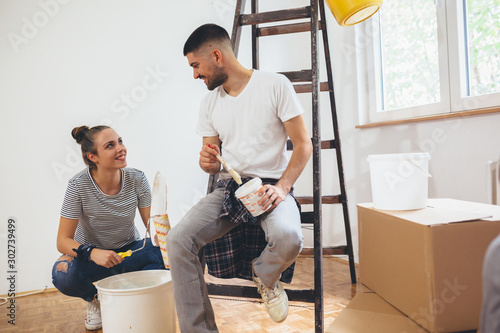 happy couple decorating indoor walls of their new flat