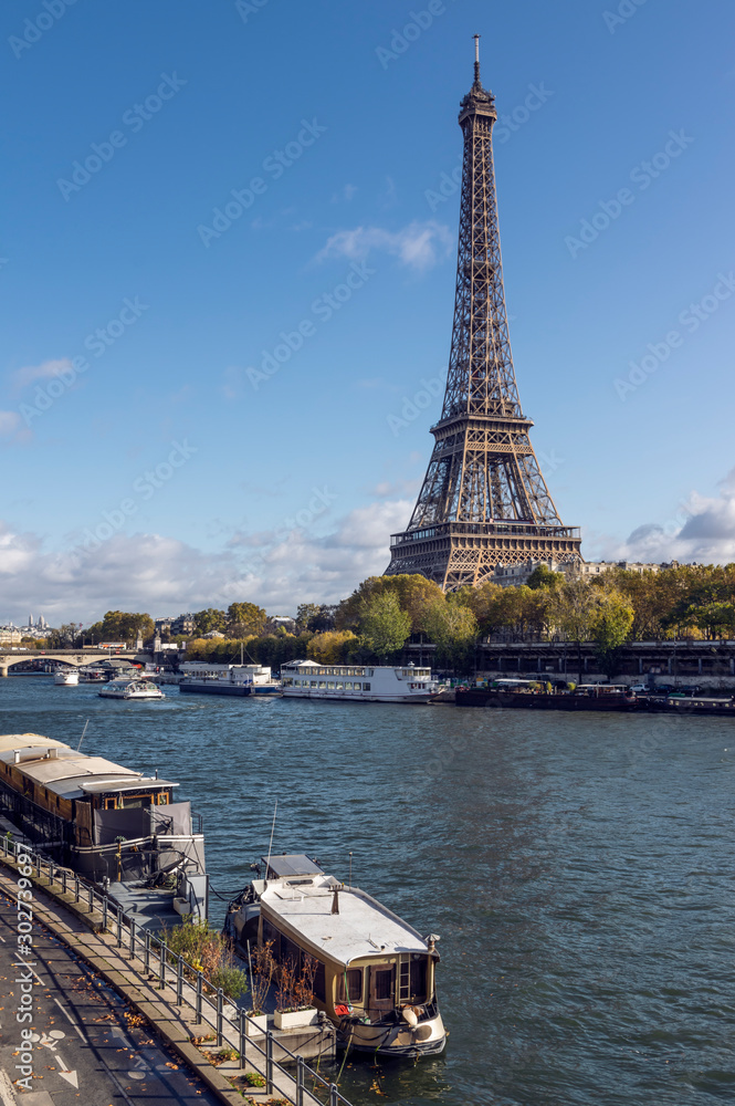 Eiffel tower across Seine River, in foreground are parked boats