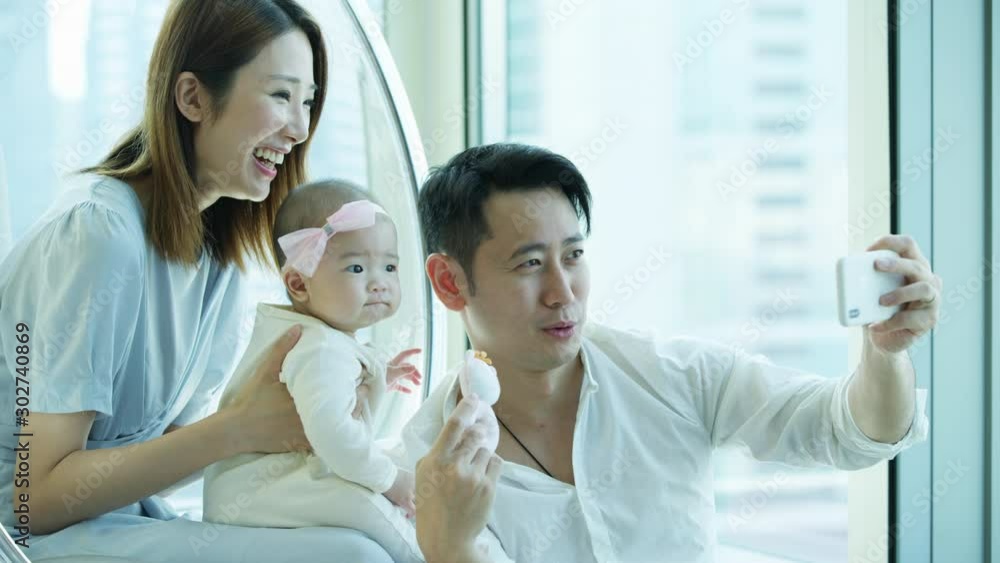 Chinese Asian parents baby enjoying smartphone wifi technology Chinese Asian parents baby enjoying smartphone wifi technology