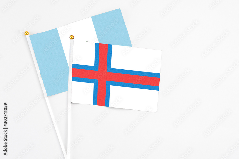 Faroe Islands and Guatemala stick flags on white background. High quality fabric, miniature national flag. Peaceful global concept.White floor for copy space.