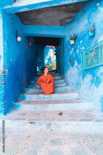 tourist in the clothes of the people of morocco sits on the steps in a blue city © nelen.ru