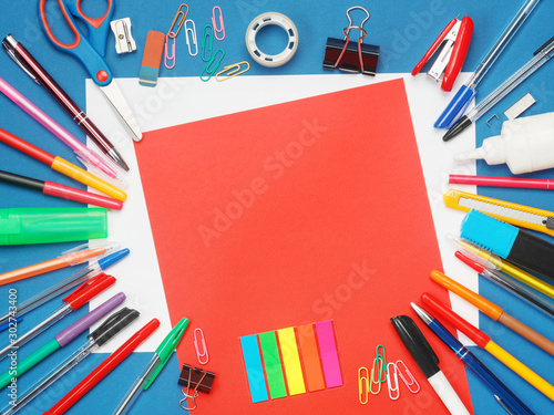 Stationery with blank red paper on blue background. Education concept with copy space for your text. Flat layout, top view. © Bondarau