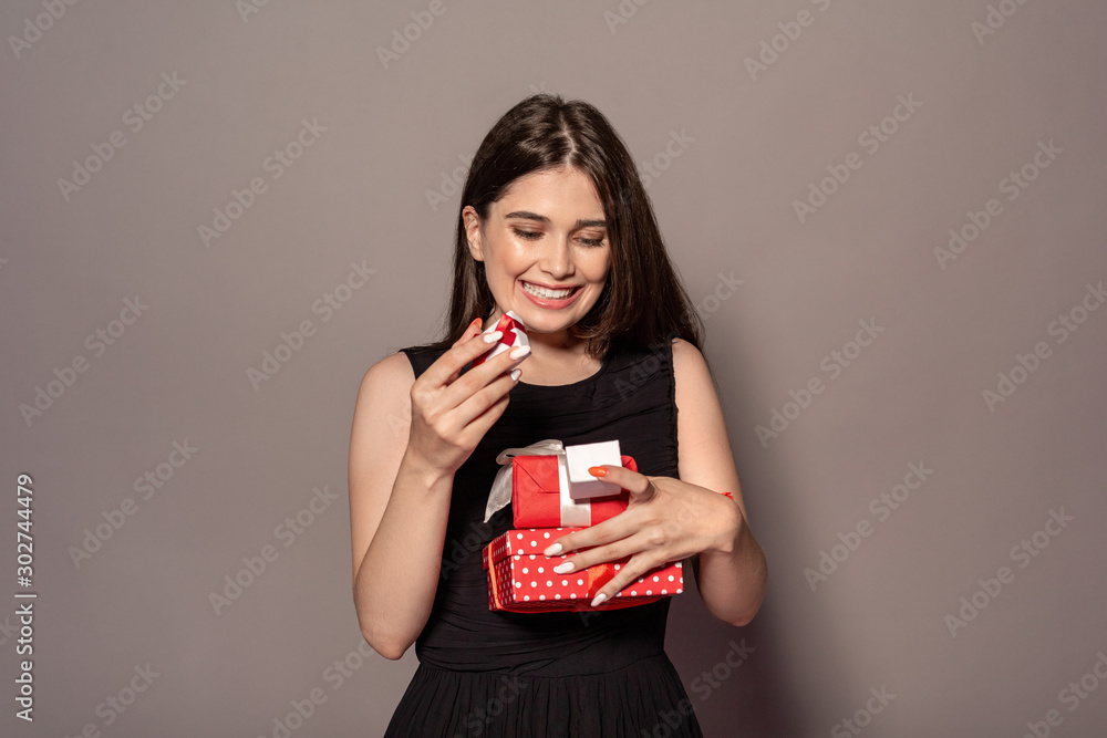 Freestyle. Young girl in dress standing studio isolated on grey with present boxes smiling cheerful Freestyle. Young girl in dress standing studio isolated on grey with present boxes smiling cheerful