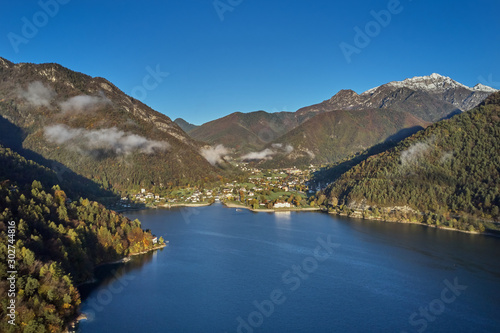 Panoramic view of the mountains and lake Pieve di Ledro, Italy. Autumn season, the reflection in the water of the mountains, trees, blue sky
