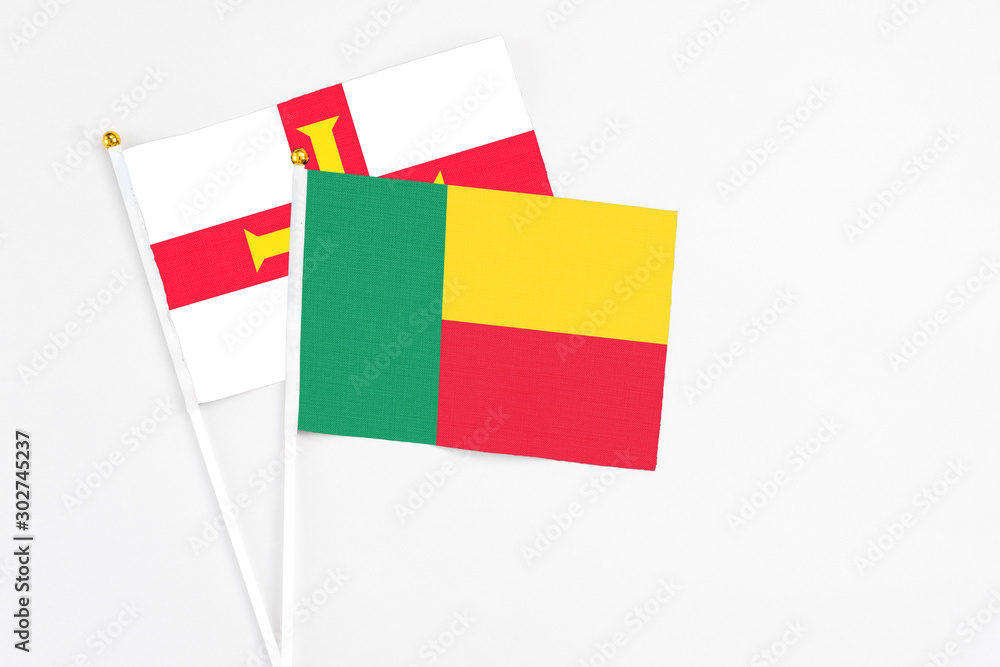 Benin and Guernsey stick flags on white background. High quality fabric, miniature national flag. Peaceful global concept.White floor for copy space. Benin and Guernsey stick flags on white background. High quality fabric, miniature national flag. Peaceful global concept.White floor for copy space.