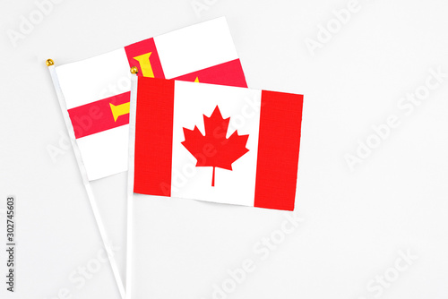 Canada and Guernsey stick flags on white background. High quality fabric, miniature national flag. Peaceful global concept.White floor for copy space.