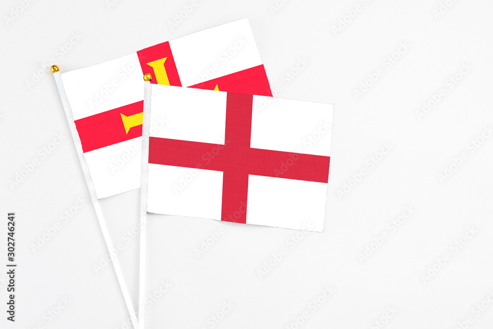 England and Guernsey stick flags on white background. High quality fabric, miniature national flag. Peaceful global concept.White floor for copy space.