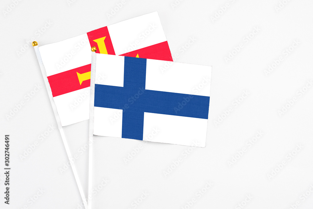Finland and Guernsey stick flags on white background. High quality fabric, miniature national flag. Peaceful global concept.White floor for copy space.