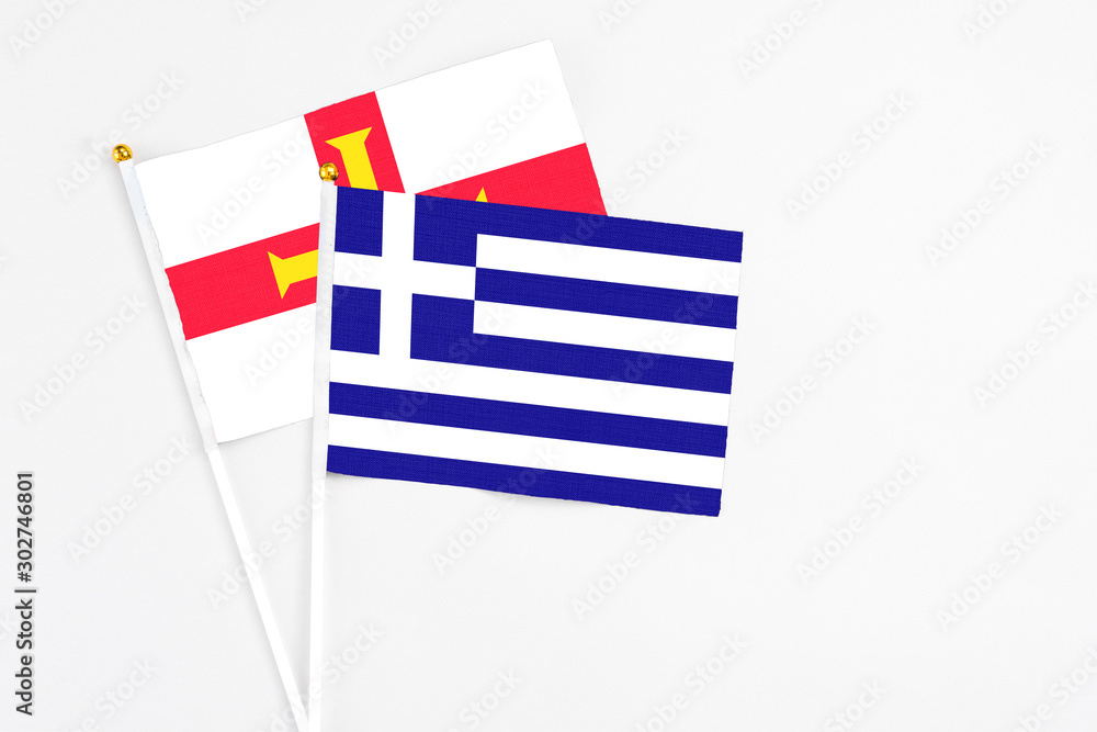 Obraz premium Greece and Guernsey stick flags on white background. High quality fabric, miniature national flag. Peaceful global concept.White floor for copy space.