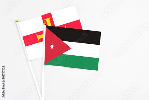 Jordan and Guernsey stick flags on white background. High quality fabric, miniature national flag. Peaceful global concept.White floor for copy space. photo