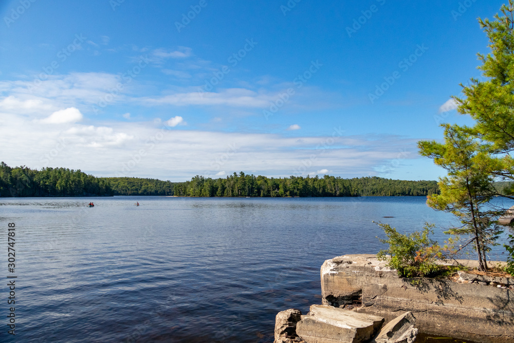 Old dock ruins on Booth's Rock Trail with view of canoers on Rock Lake ...