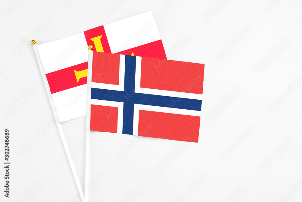 Norway and Guernsey stick flags on white background. High quality fabric, miniature national flag. Peaceful global concept.White floor for copy space.