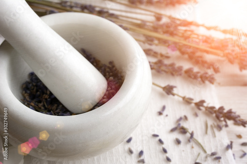 making organic cosmetics with dried lavender In marble mortar and pestle on white wooden background top view. tonned image