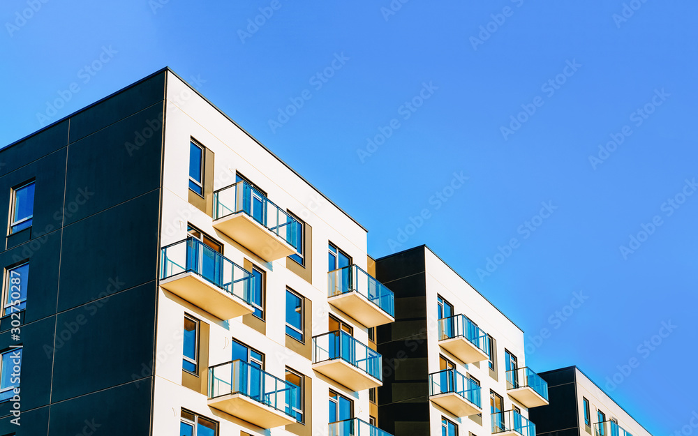 Fragment of Modern residential apartment with flat buildings exterior. Detail of New luxury house and home complex. Part of City Real estate property and condo architecture. Copy space. Blue sky