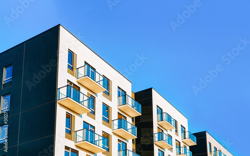 Obraz na płótnie Fragment of Modern residential apartment with flat buildings exterior. Detail of New luxury house and home complex. Part of City Real estate property and condo architecture. Copy space. Blue sky w salonie