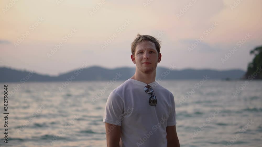 Portrait of Young Handsome Traveling Man Looking At Camera With Tropical Island Sunset Scene Behind Portrait of Young Handsome Traveling Man Looking At Camera With Tropical Island Sunset Scene Behind