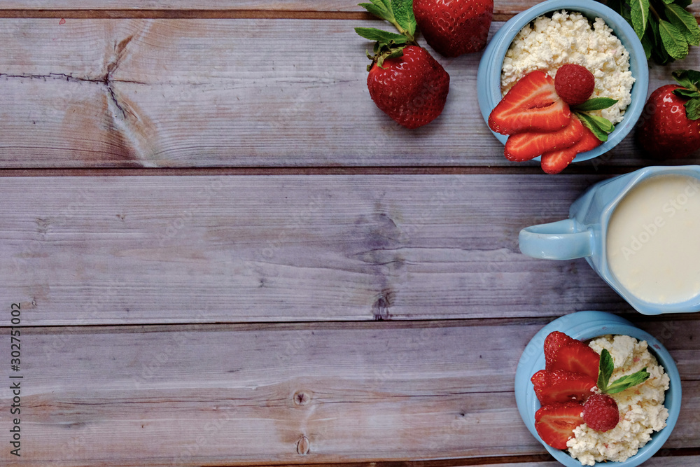 Fresh farm cottage cheese with strawberries-a great Breakfast for those who care about health. Two blue bowls of cottage cheese are on a wooden table. Selective focus. Copy space.  