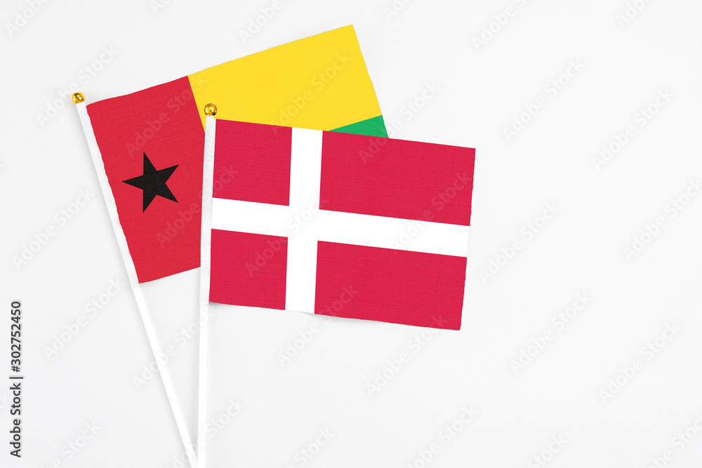 Denmark and Guinea Bissau stick flags on white background. High quality fabric, miniature national flag. Peaceful global concept.White floor for copy space.