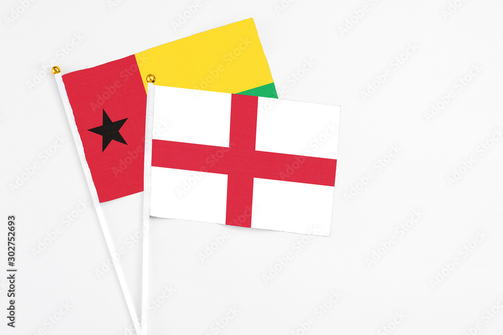 England and Guinea Bissau stick flags on white background. High quality fabric, miniature national flag. Peaceful global concept.White floor for copy space.