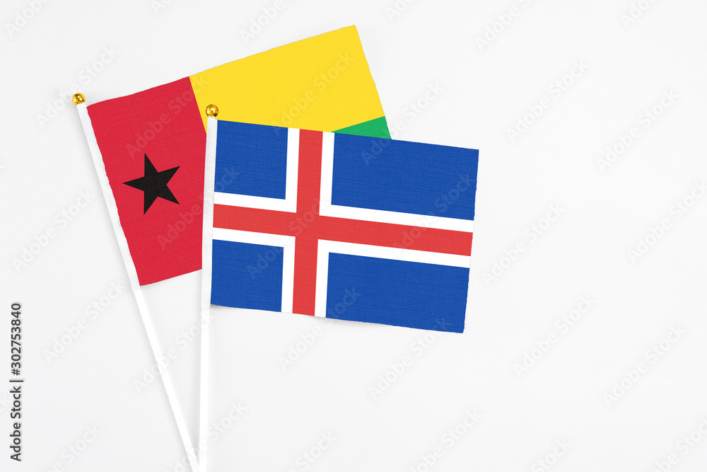 Iceland and Guinea Bissau stick flags on white background. High quality fabric, miniature national flag. Peaceful global concept.White floor for copy space.