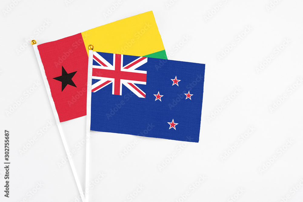 New Zealand and Guinea Bissau stick flags on white background. High quality fabric, miniature national flag. Peaceful global concept.White floor for copy space. New Zealand and Guinea Bissau stick flags on white background. High quality fabric, miniature national flag. Peaceful global concept.White floor for copy space.