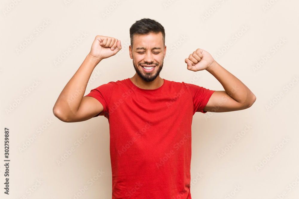 Young south-asian man celebrating a special day, jumps and raise arms with energy. Young south-asian man celebrating a special day, jumps and raise arms with energy.