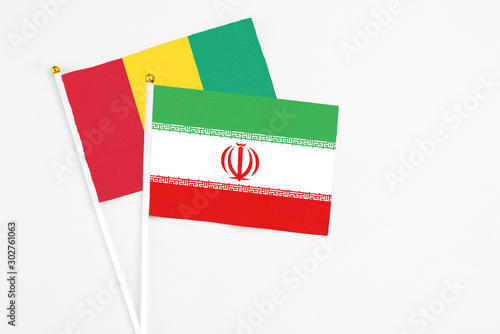 Iran and Guinea stick flags on white background. High quality fabric, miniature national flag. Peaceful global concept.White floor for copy space.